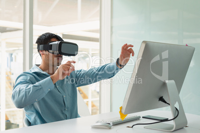 Male executive using virtual reality headset at desk