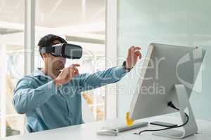 Male executive using virtual reality headset at desk