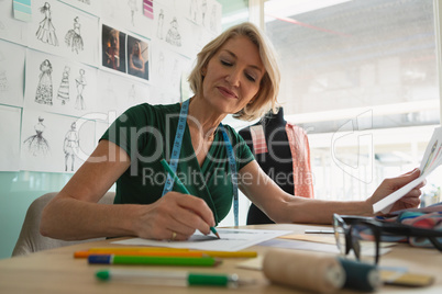 Female fashion designer drawing sketch on a table