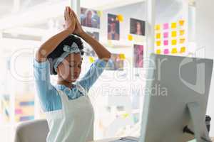 Female graphic designer performing yoga at desk