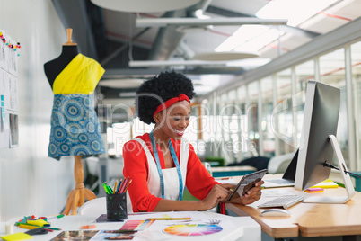 Female fashion designer using digital tablet at desk