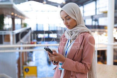 Businesswoman in hijab using mobile phone in a modern office