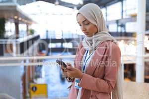 Businesswoman in hijab using mobile phone in a modern office