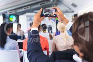 Close-up of Businessman clicking photo of business seminar with mobile phone