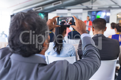 Close-up of Businessman clicking photo of business seminar with mobile phone