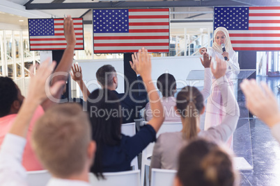 Business people raising their hands while attending business seminar in conference meeting