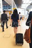Businesswoman walking with luggage in corridor at office