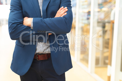 Businessman standing with arms crossed in the corridor at office