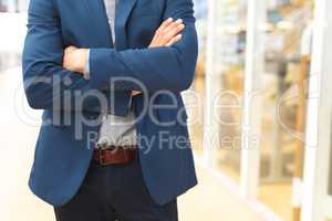 Businessman standing with arms crossed in the corridor at office