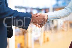 Business people shaking hands with each other in corridor at office