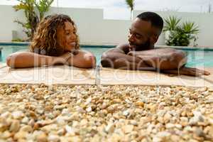 Couple leaning on the edge of a swimming pool and looking each other