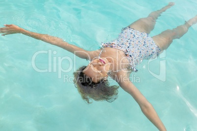 Woman with eyes closed floating in swimming pool at the backyard of home