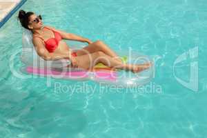 Woman in bikini relaxing on a inflatable tube in swimming pool at the backyard of home