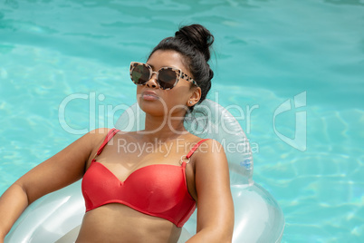 Woman in bikini relaxing on a inflatable tube in swimming pool at the backyard of home