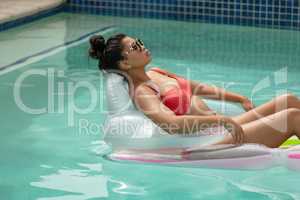 Woman in bikini relaxing on inflatable tube in swimming pool at the backyard of home