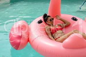 Woman in bikini relaxing on a inflatable tube in swimming pool at the backyard of home