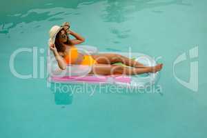 Woman in bikini relaxing on a inflatable tube in swimming pool at the backyard of home