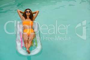 Woman in bikini relaxing on a inflatable tube in swimming pool at the backyard of home