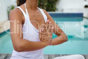 Woman performing yoga near swimming pool in the backyard