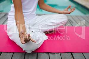 Woman performing yoga near swimming pool in the backyard