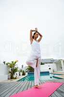 Woman performing yoga near swimming pool in the backyard