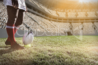 Composite image of rugby player preparing to kick the ball on field.