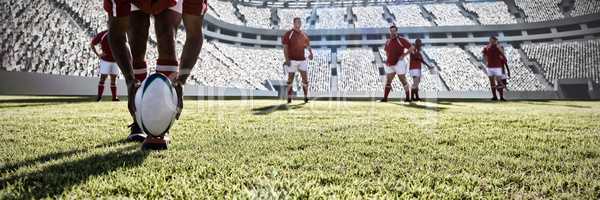 Composite image of rugby player putting ball on the field.