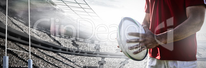 Composite image of rugby player holding football at field. Composite image of rugby player holding football at field.