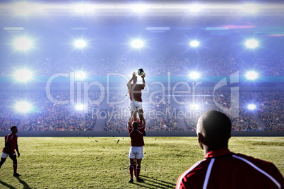 Composite image of rugby player catching the ball in the air.