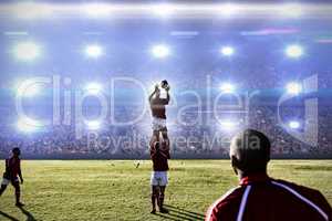 Composite image of rugby player catching the ball in the air.