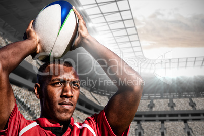 Composite image of rugby player holding football above head.