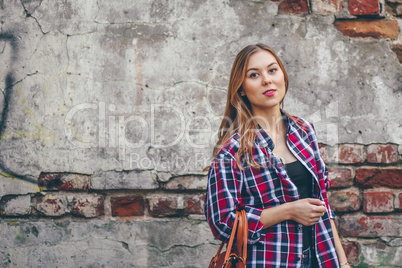 Beautiful girl is standing against brick wall