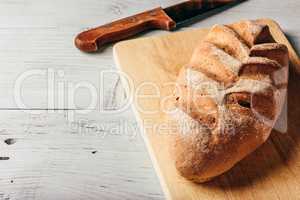 Rye loaf on cutting board with knife.