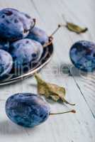 Plums on wooden surface with leaves