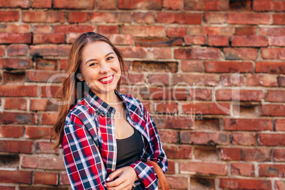 Portrait of young woman against brick wall