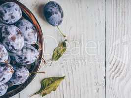Plums on plate over wooden surface