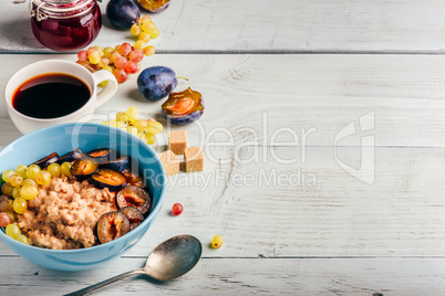 Porridge with plum, grapes and cup of coffee