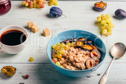 Porridge with plum, grapes and cup of coffee
