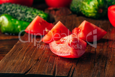 Sliced tomatoes on cutting board and cucumbers with chili pepper