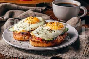 Italian toasts with vegetables and fried eggs on white plate and