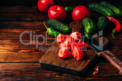 Sliced tomatoes on cutting board and cucumbers with chili pepper