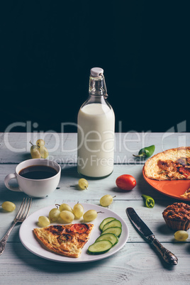 Frittata and fruits, vegetables, bottle of milk, cup of coffee.