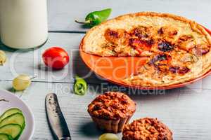 Frittata with muffins over light wooden background.