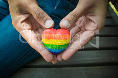 Decorative Heart with rainbow stripes in female hands. LGBT pride flag, symbol of lesbian, gay, bisexual, transgender for social movements. Homosexual love, Human rights concept. Copy space.