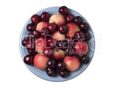 Sweet cherries and ripe juicy nectarines in a dish, on white bac