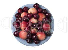 Sweet cherries and ripe juicy nectarines in a dish, on white bac