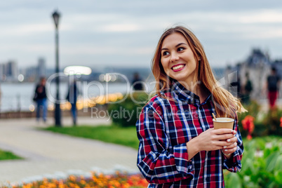 Beautiful young woman holding coffee cup and smiling