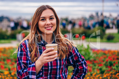 Beautiful young woman holding coffee cup and smiling