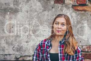 Beautiful girl is standing against brick wall
