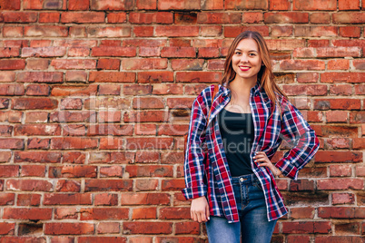 Portrait of young woman standing against brick wall